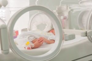 newborn baby hooked up to medical equipment in hospital bed